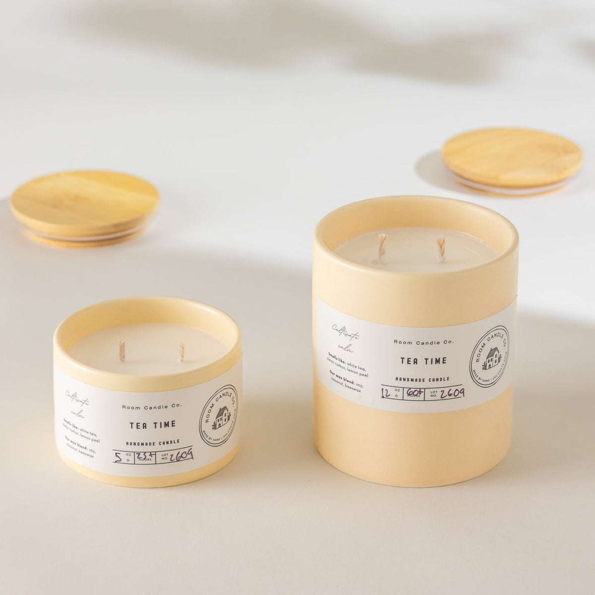 Two Tea Time candles by Room Candle Co. in 5 oz and 12 oz sizes, displayed in buttercream ceramic vessels against a plain background.