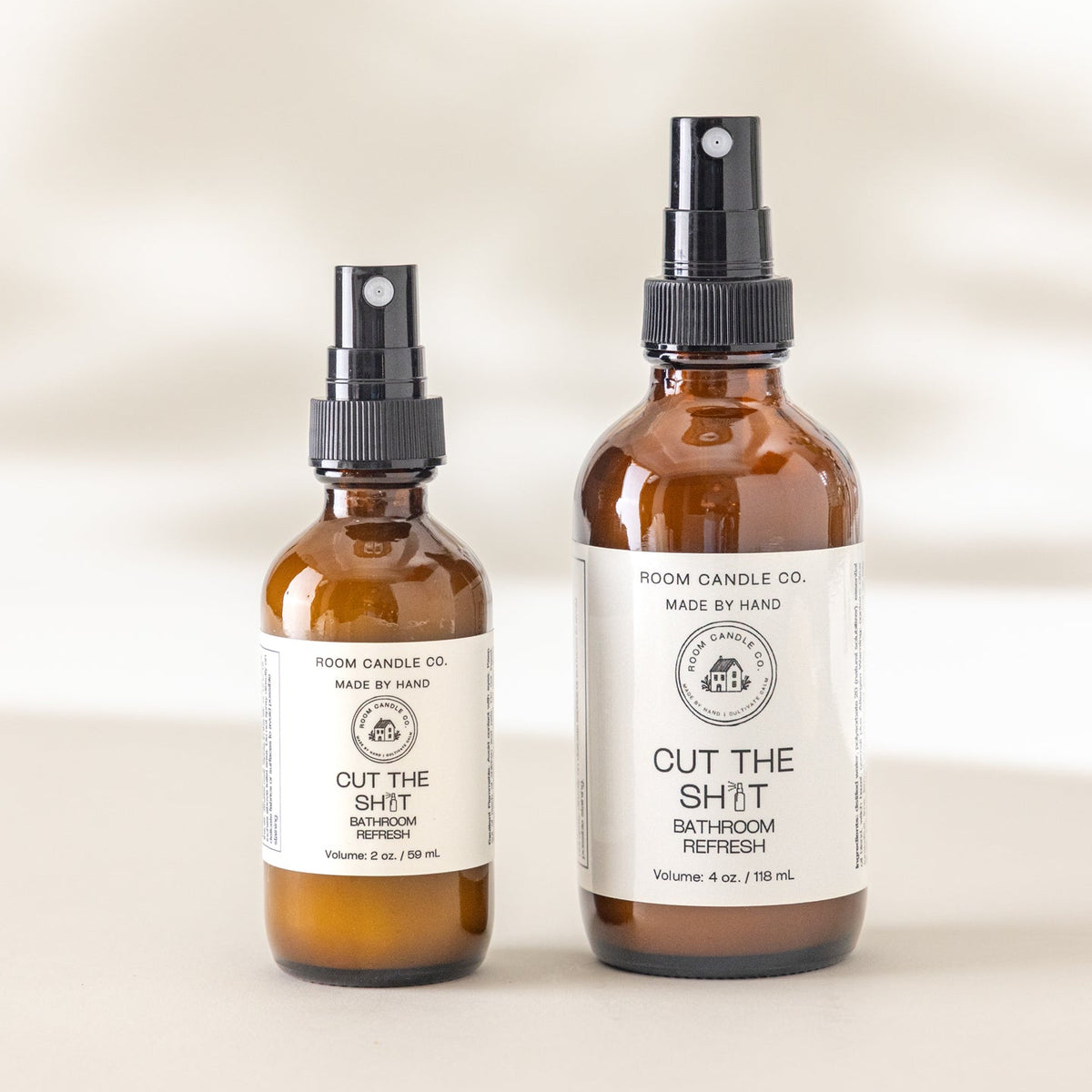 Room Candle Co.’s Cut the Sh*t bathroom refresh spray in 2 oz and 4 oz bottles displayed side by side against a plain background.