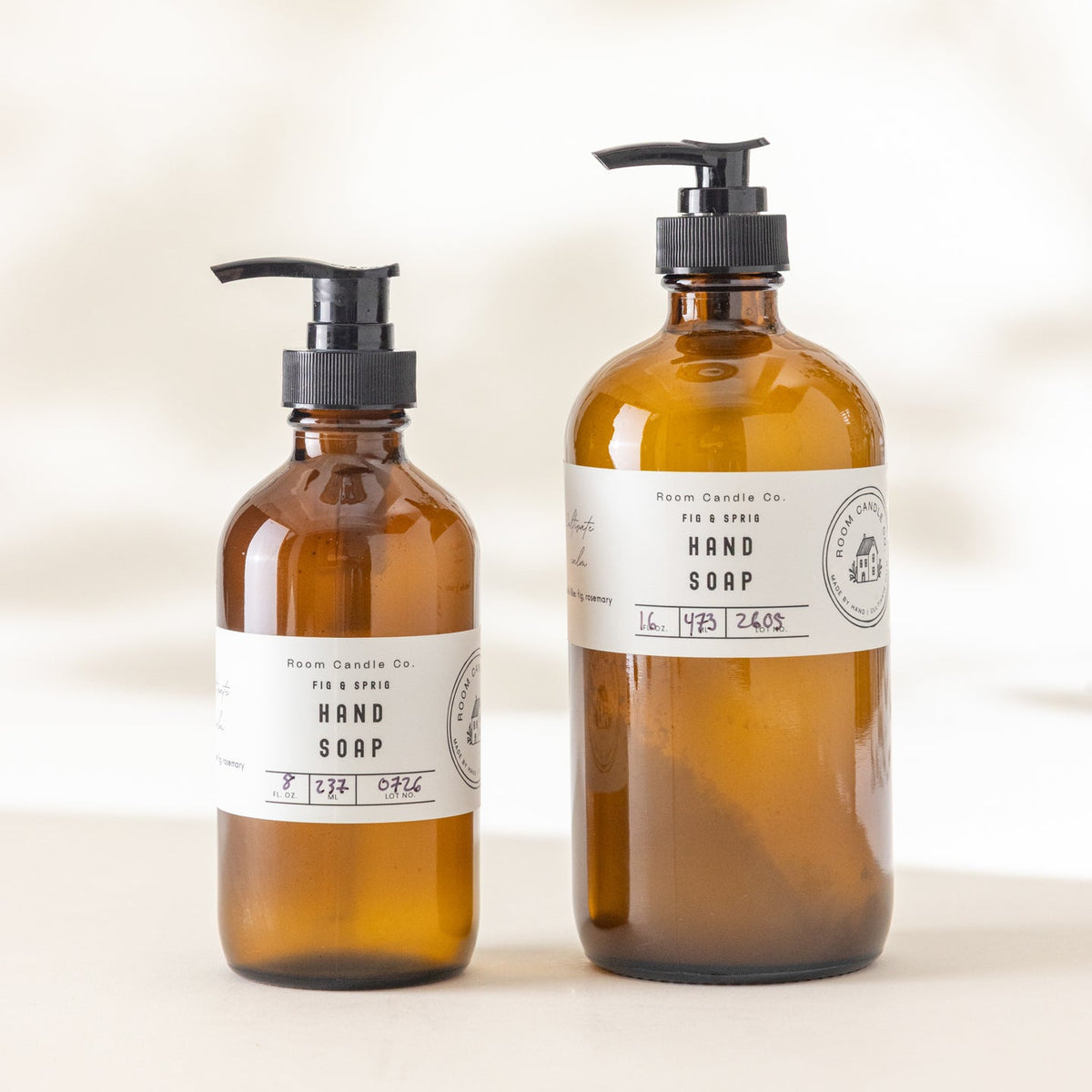 Two sizes of Fig and Sprig Liquid Hand Soap by Room Candle Co. displayed side by side against a plain background.