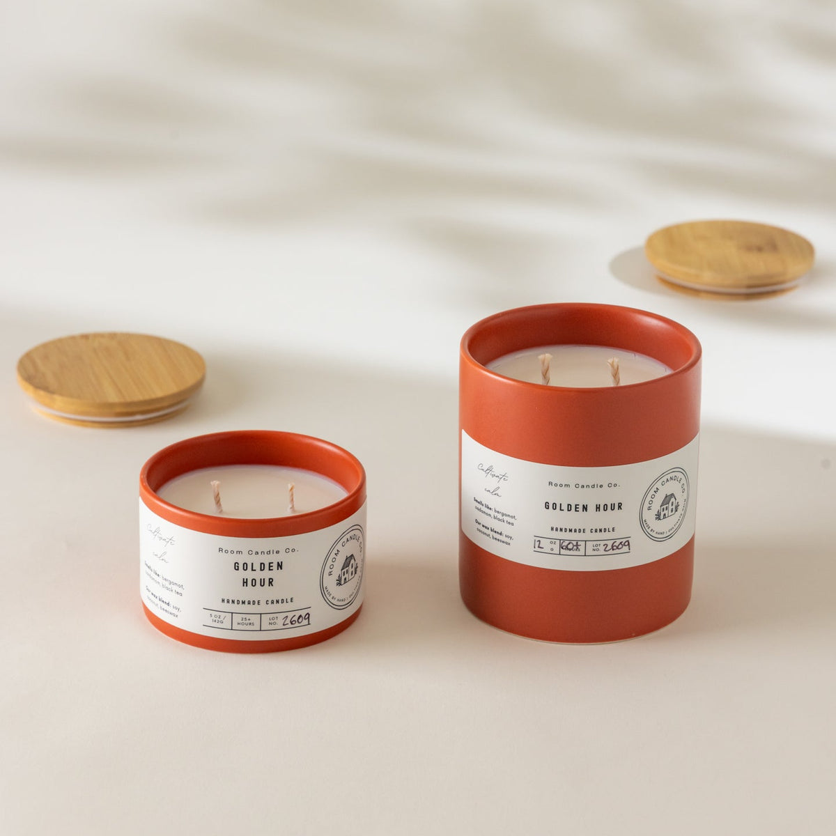 Two Golden Hour candles by Room Candle Co. in 5 oz and 12 oz sizes, displayed in burnt sienna ceramic vessels against a plain background.