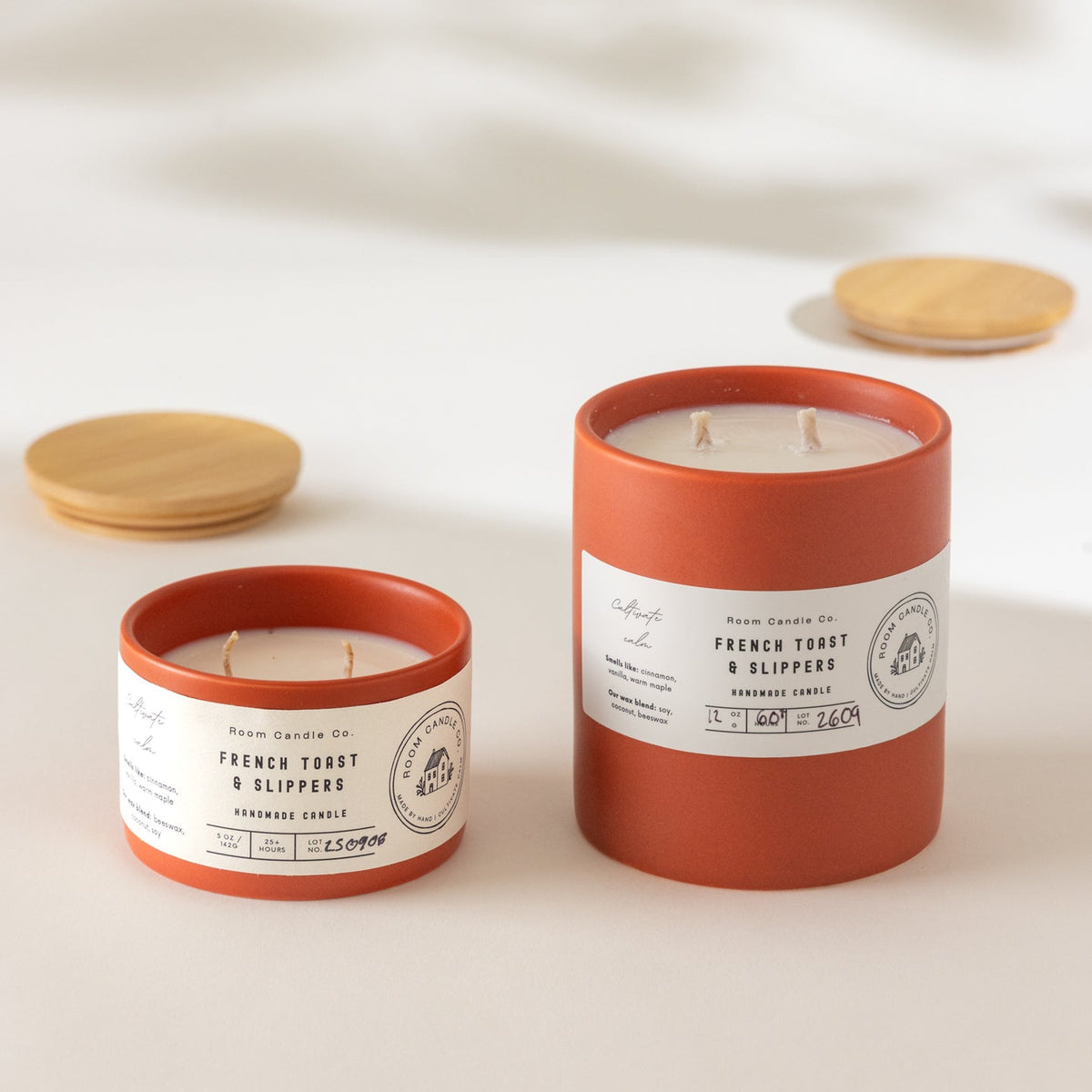 Two French Toast and Slippers candles by Room Candle Co. in 5 oz and 12 oz sizes, displayed in burnt sienna ceramic vessels against a plain background.